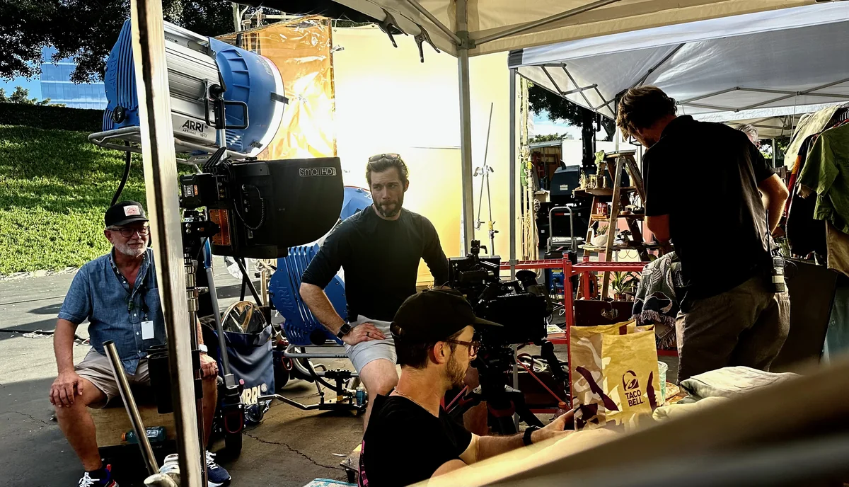 The crew working together around the camera and lighting on location.