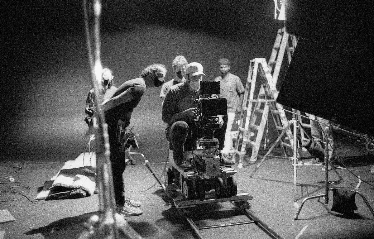 A film crew working around a cinema camera on a studio stage.